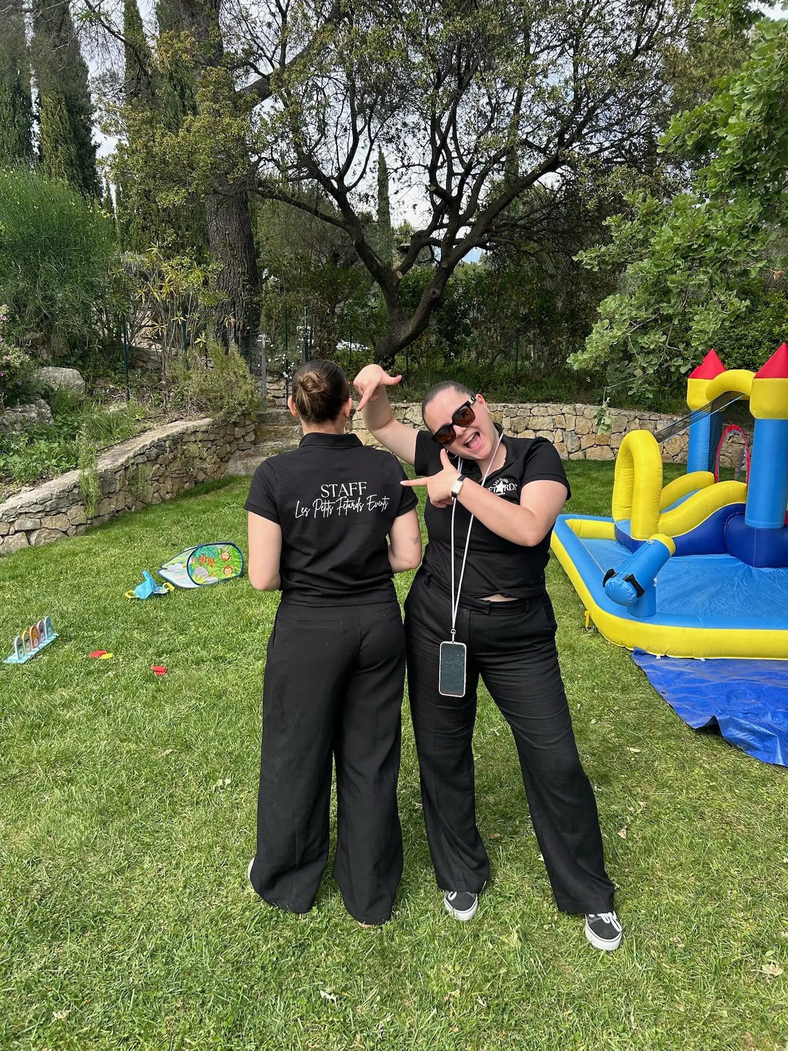 Deux animatrices échangent dans le jardin, près des jeux gonflables