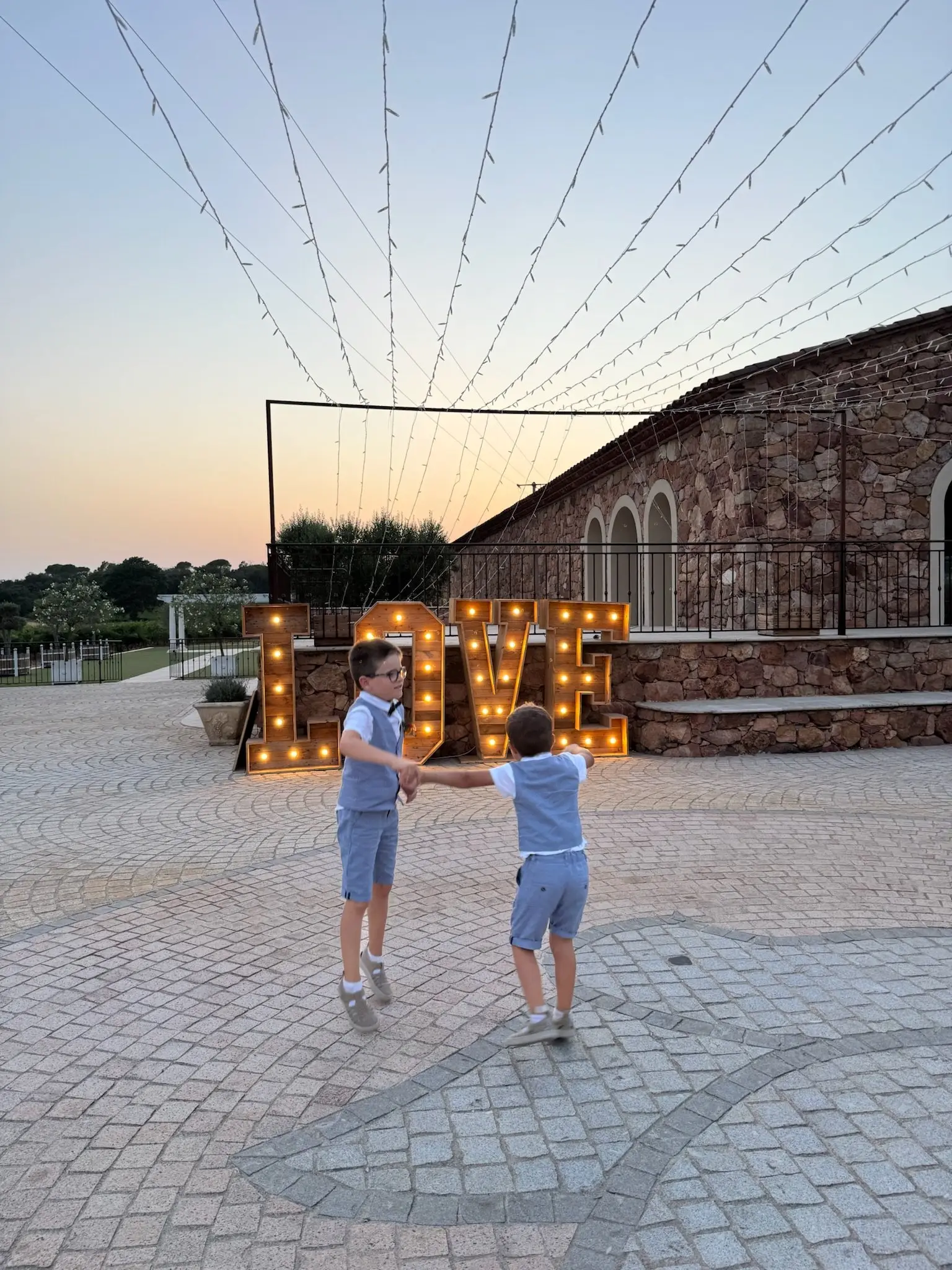 Deux enfants traversent une cour décorée de guirlandes lumineuses