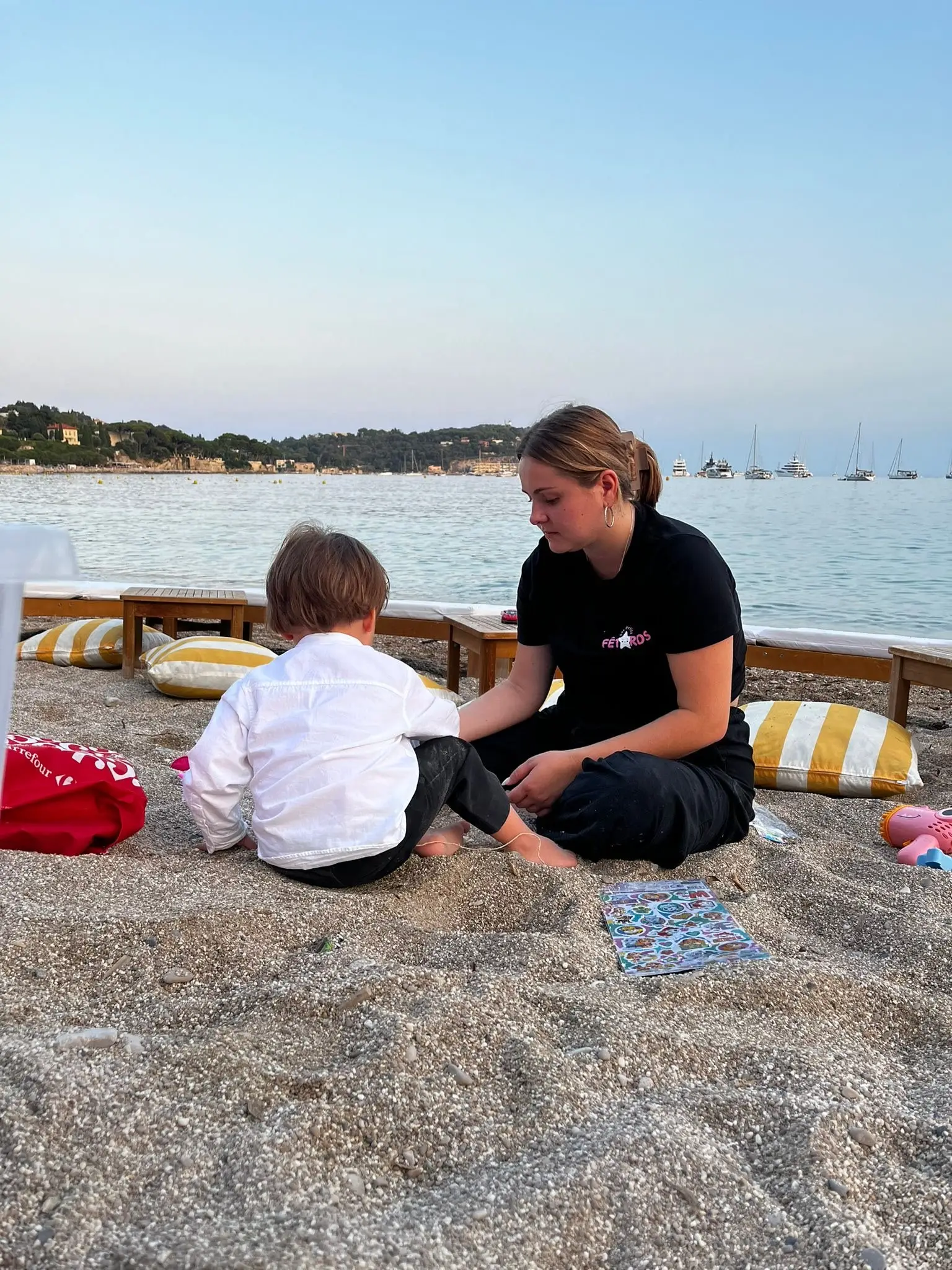 Une animatrice joue avec un enfant sur le sable au bord de la mer