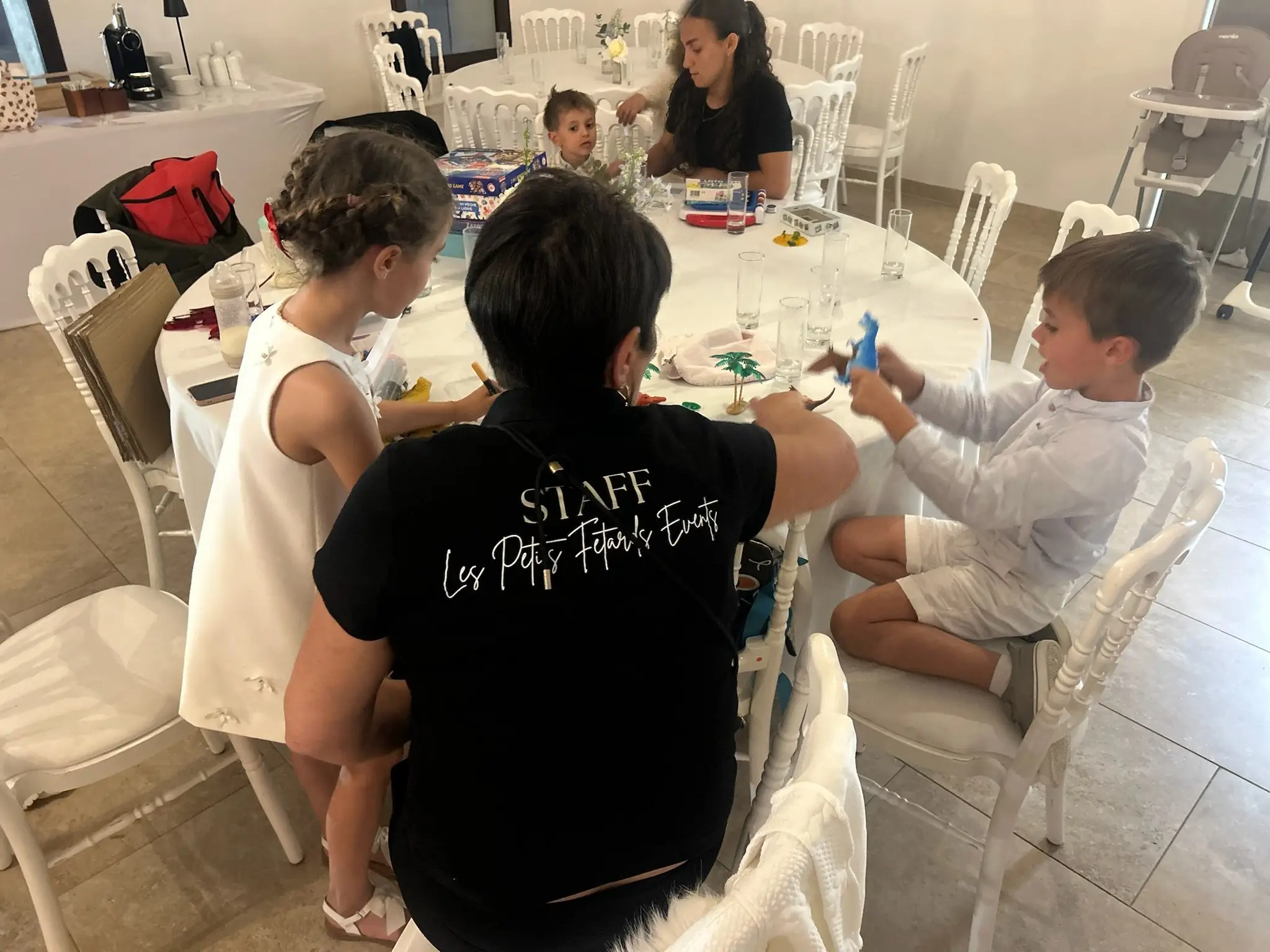 Deux animatrices encadrent les enfants autour d’une table d’activités