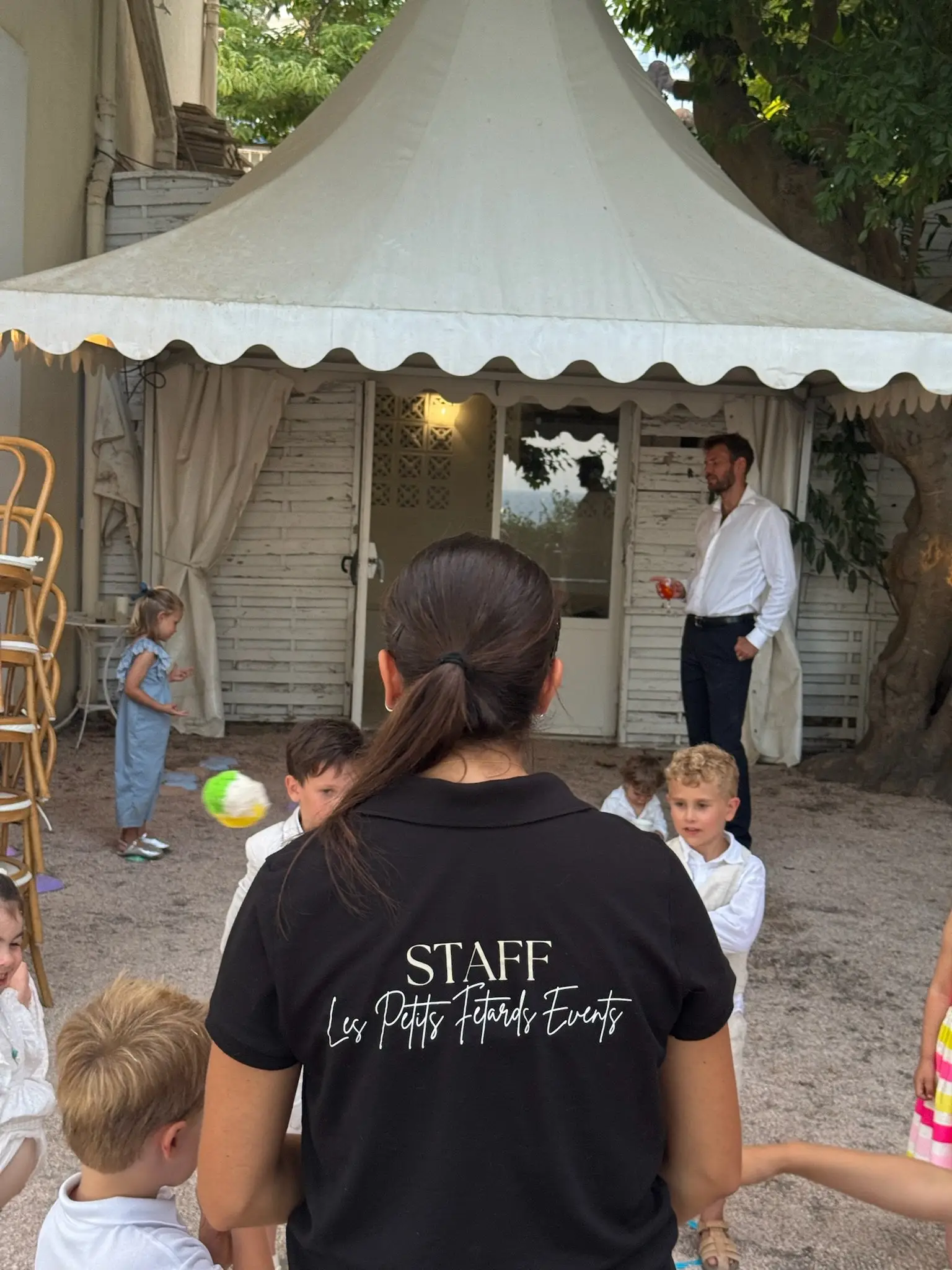 Une animatrice surveille les jeux de ballon devant une tente de réception