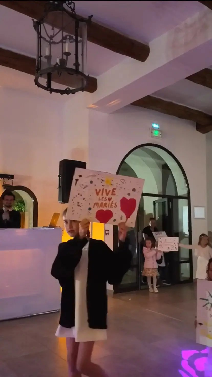 Un enfant brandit une pancarte « Vive les mariés » dans la salle de réception