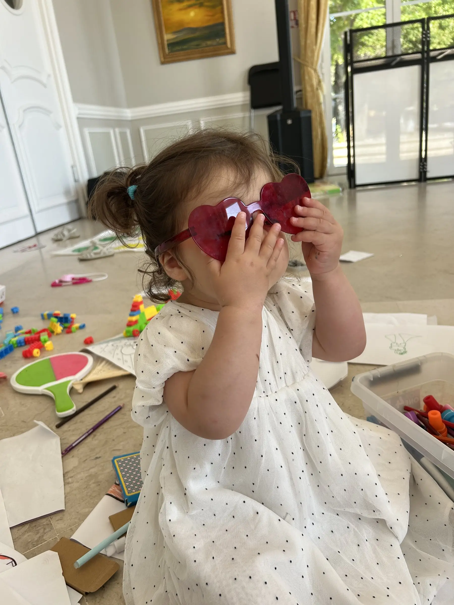 Une petite fille joue avec des lunettes en forme de cœur