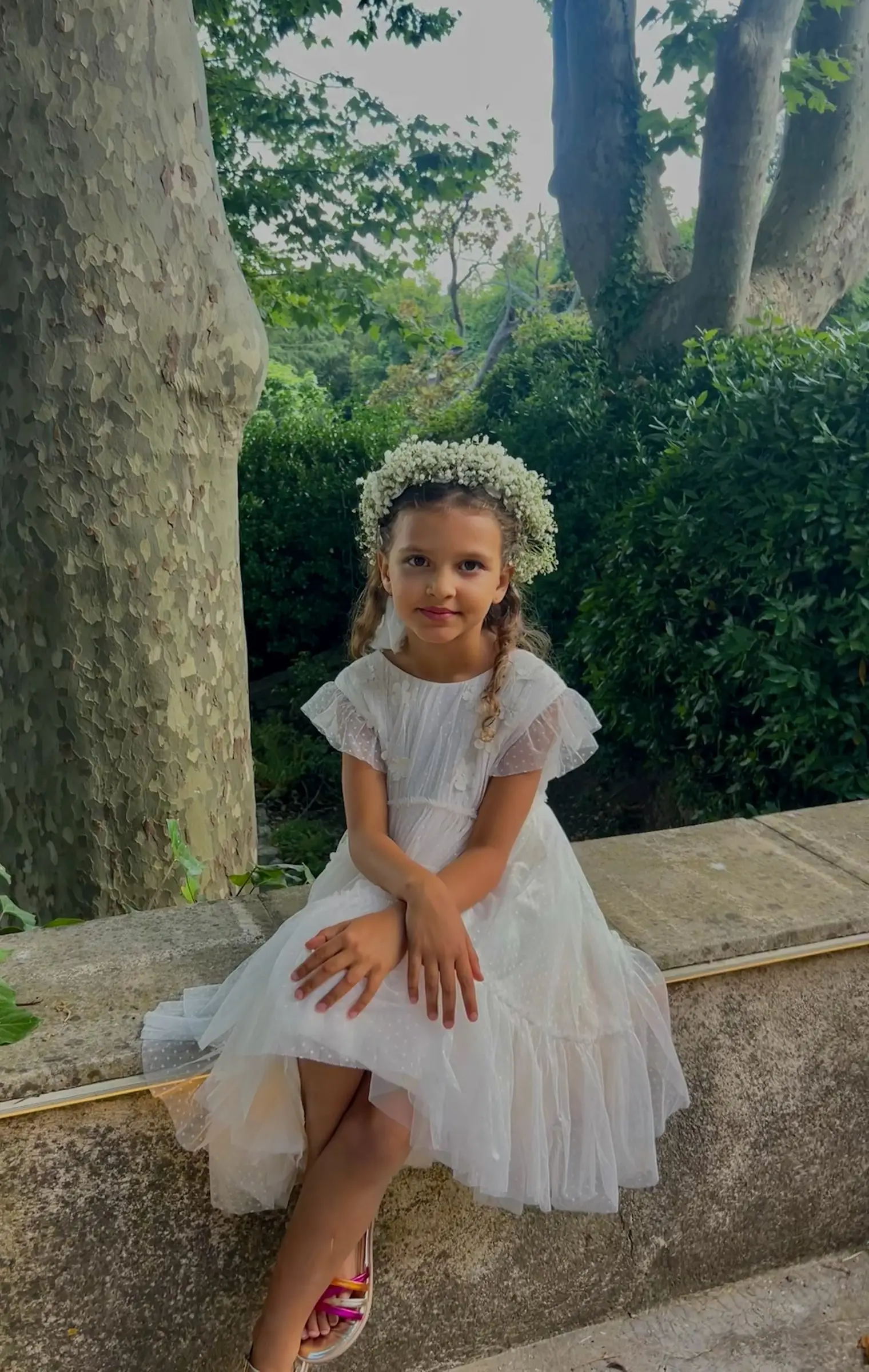 Une demoiselle d’honneur couronnée de fleurs, assise sur un muret