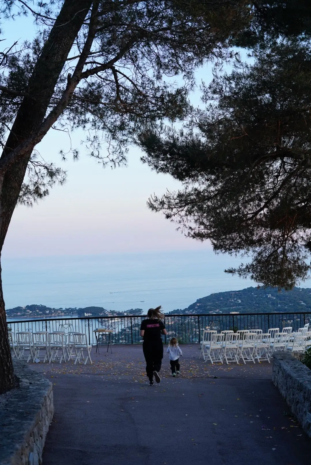 Une animatrice et un enfant dans l’allée face à la mer, sous les pins