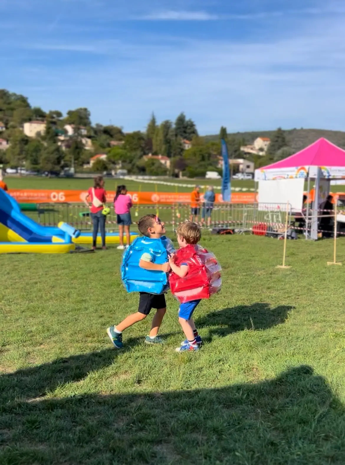 Deux enfants en bulles gonflables s’affrontent sur la pelouse d’un événement d’entreprise